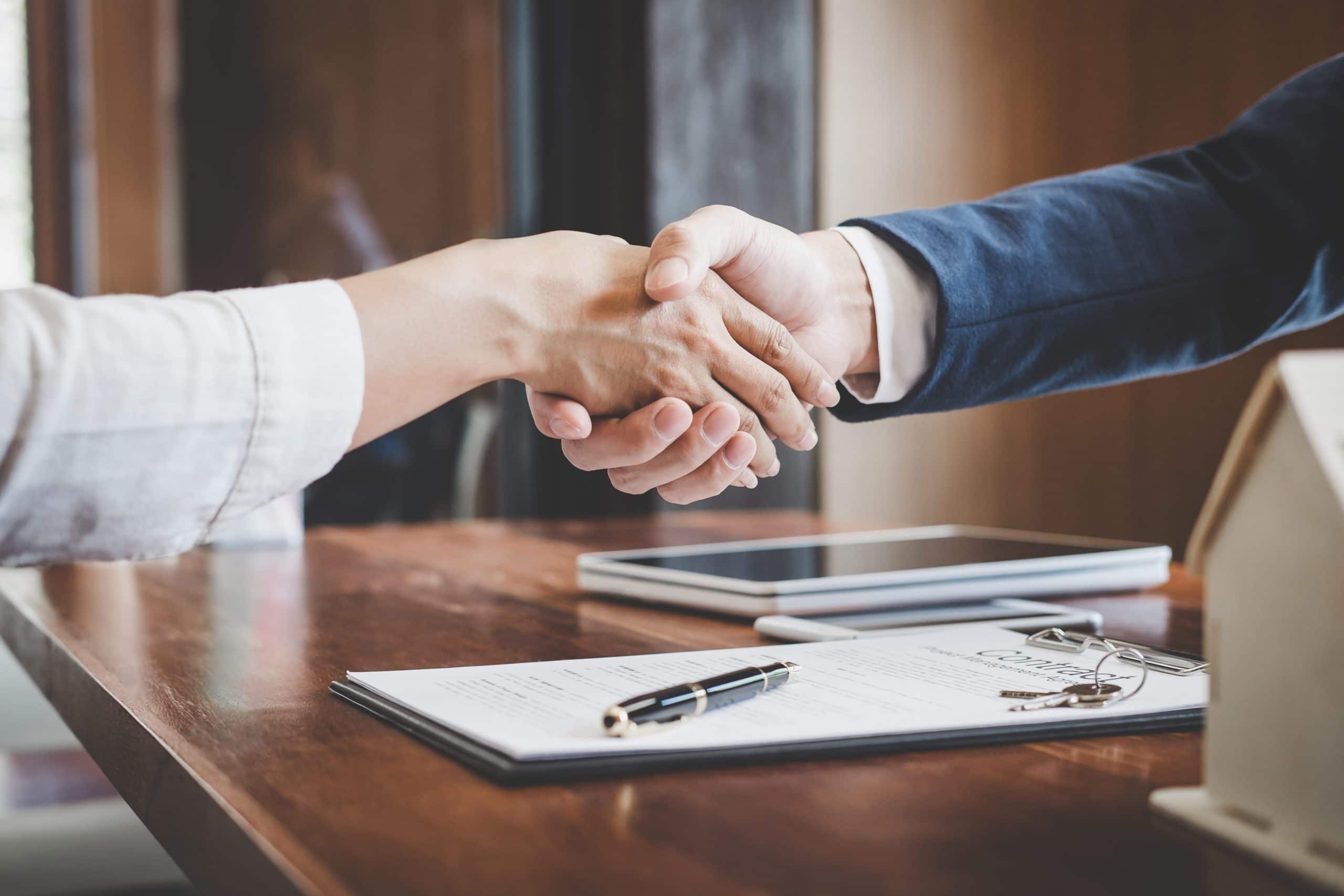 Lender and customer shaking hands together celebrating finished contract after about home insurance and investment loan, handshake and successful deal.