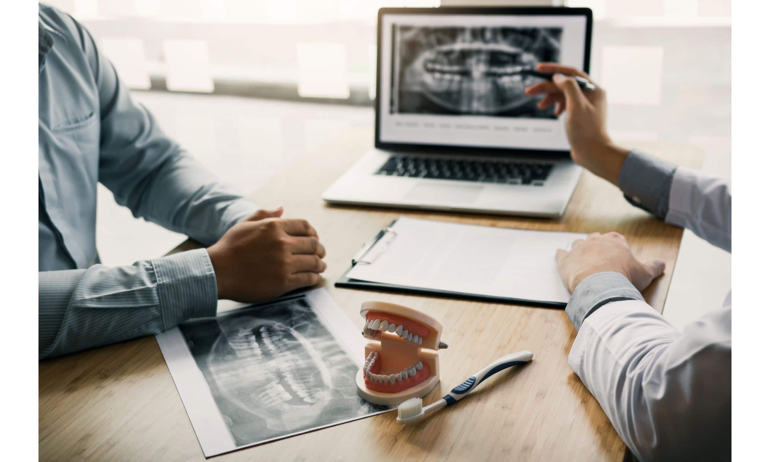 Dentists looking at x-ray image on laptop.