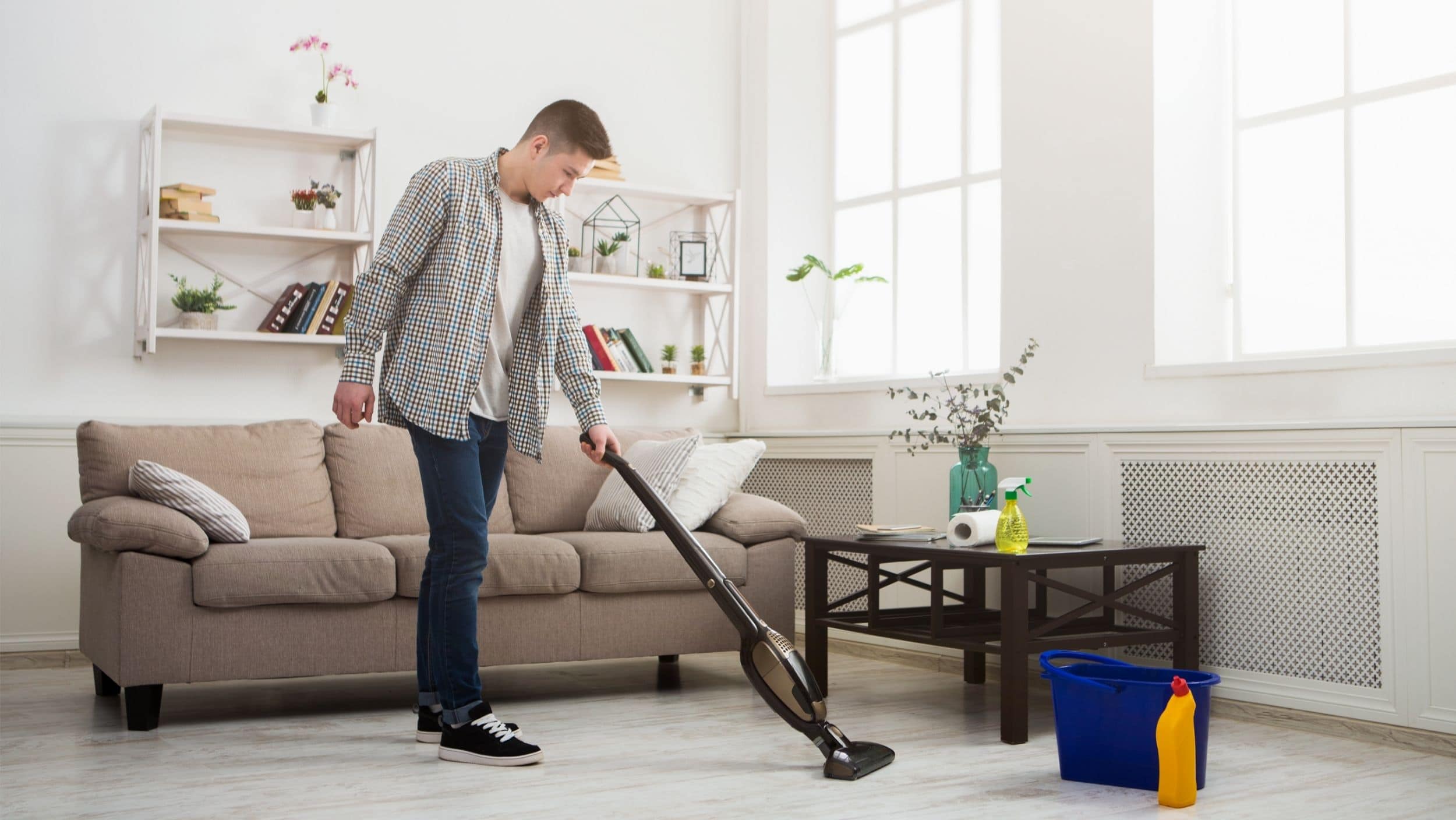 Young man cleaning house with vacuum cleaner