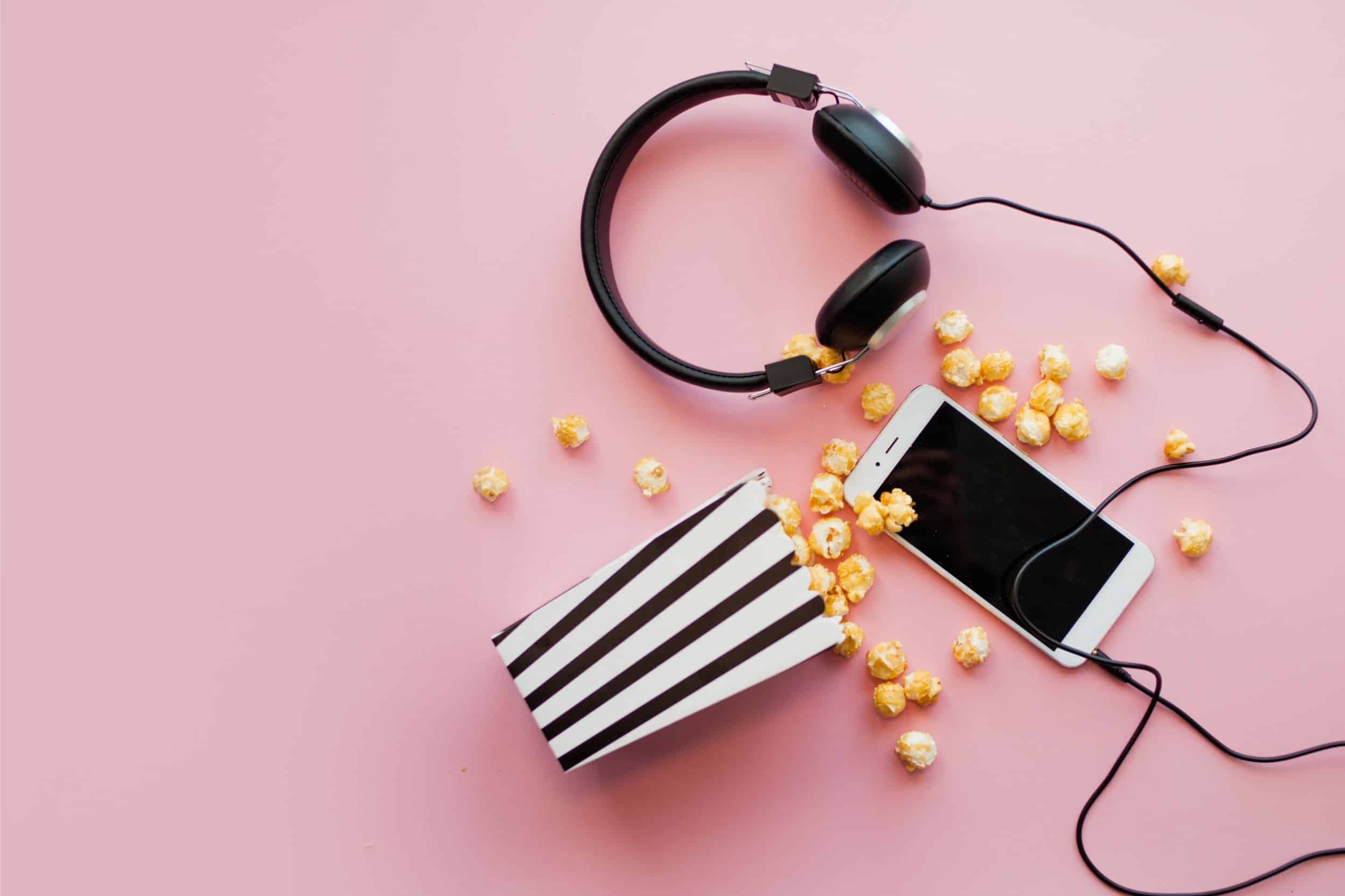 Smartphone lying next to a black and white paper striped box of popcorn