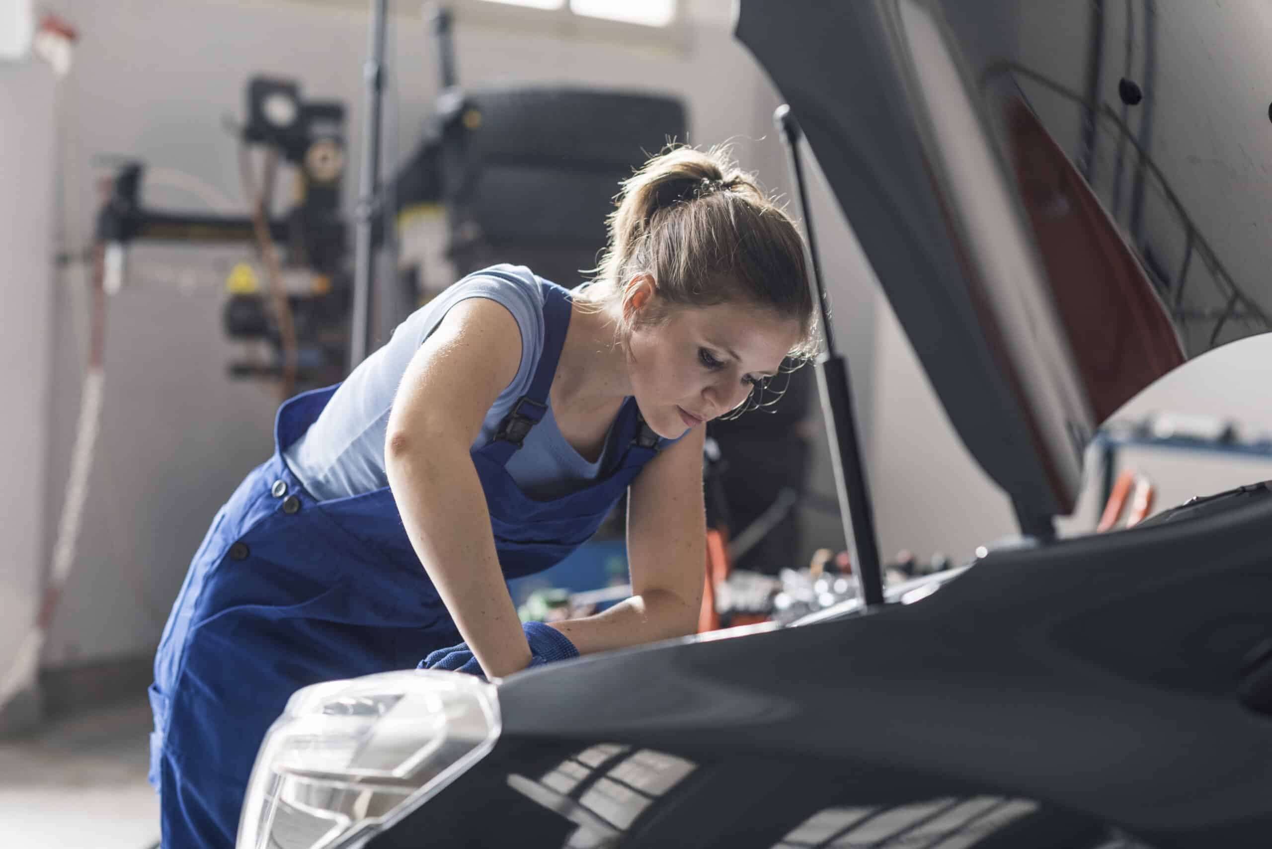 Confident female mechanic fixing a car in the auto repair shop