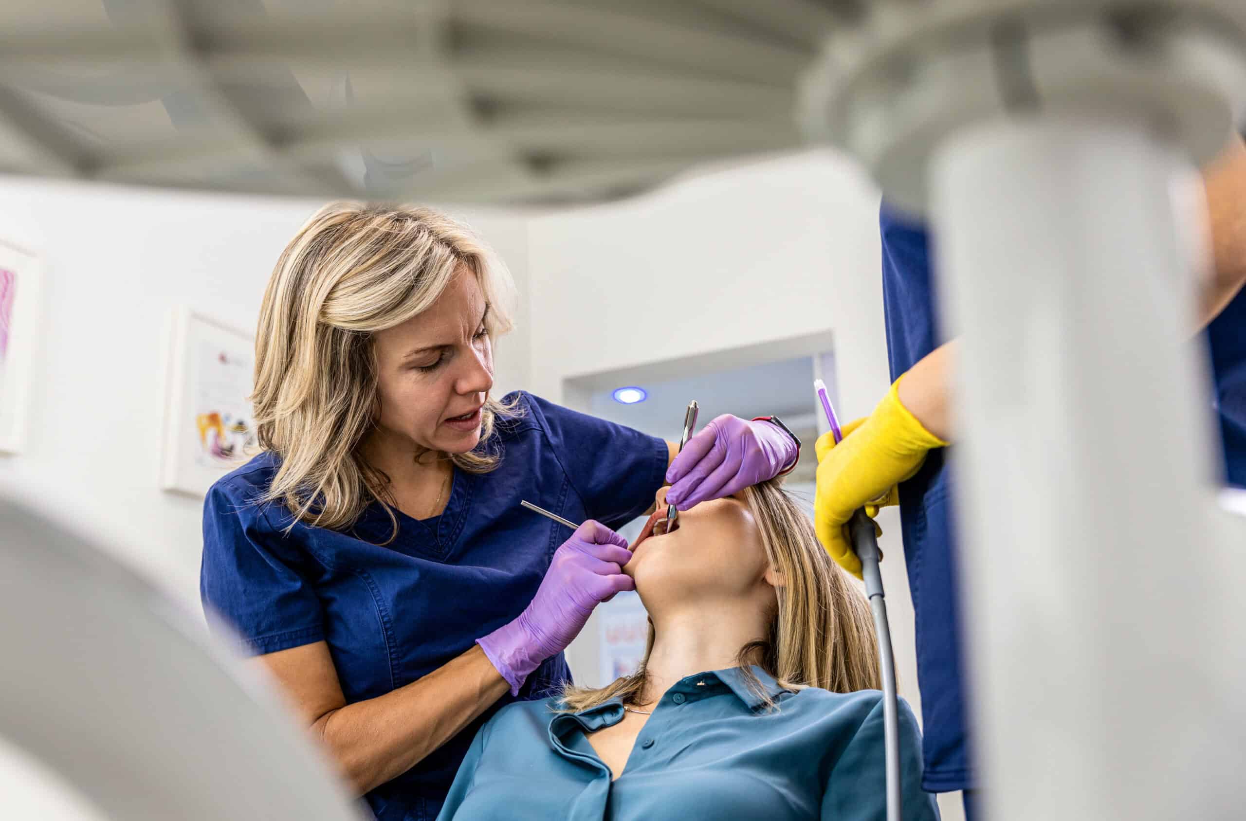 Female dentist with assistant working in dental clinic examining