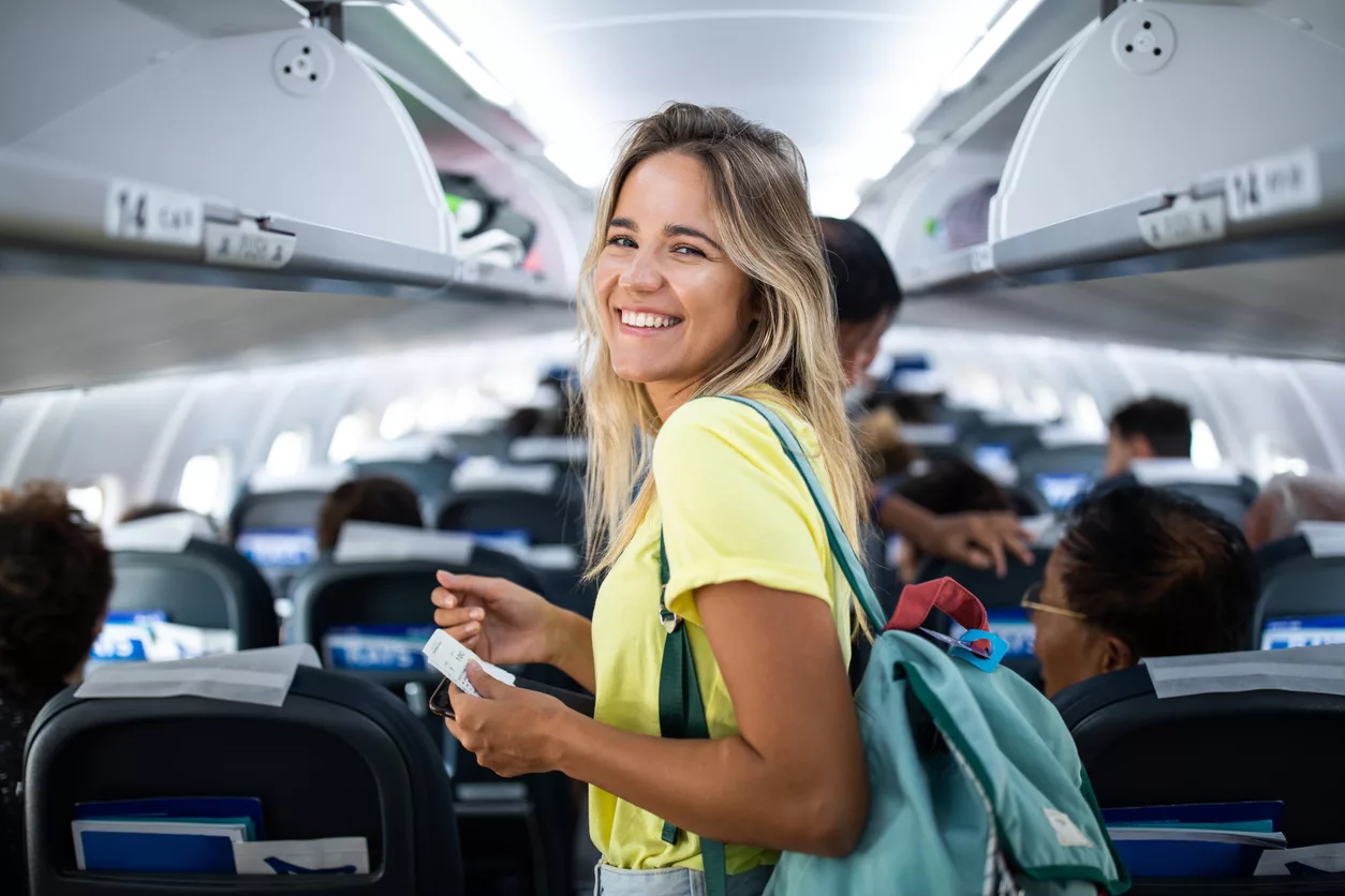 Happy woman boarding the airplane and looking at camera.